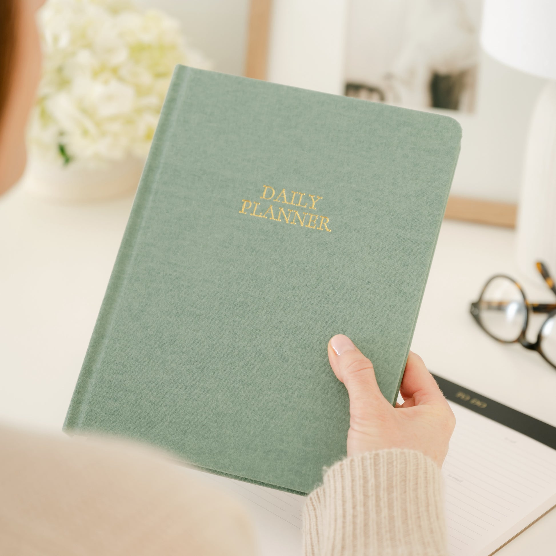 Daily sage green planner in hands