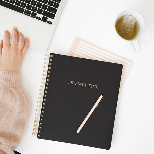 Black large weekly planner on desk with computer