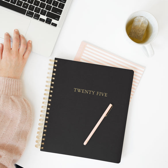 Black large weekly planner on desk with computer
