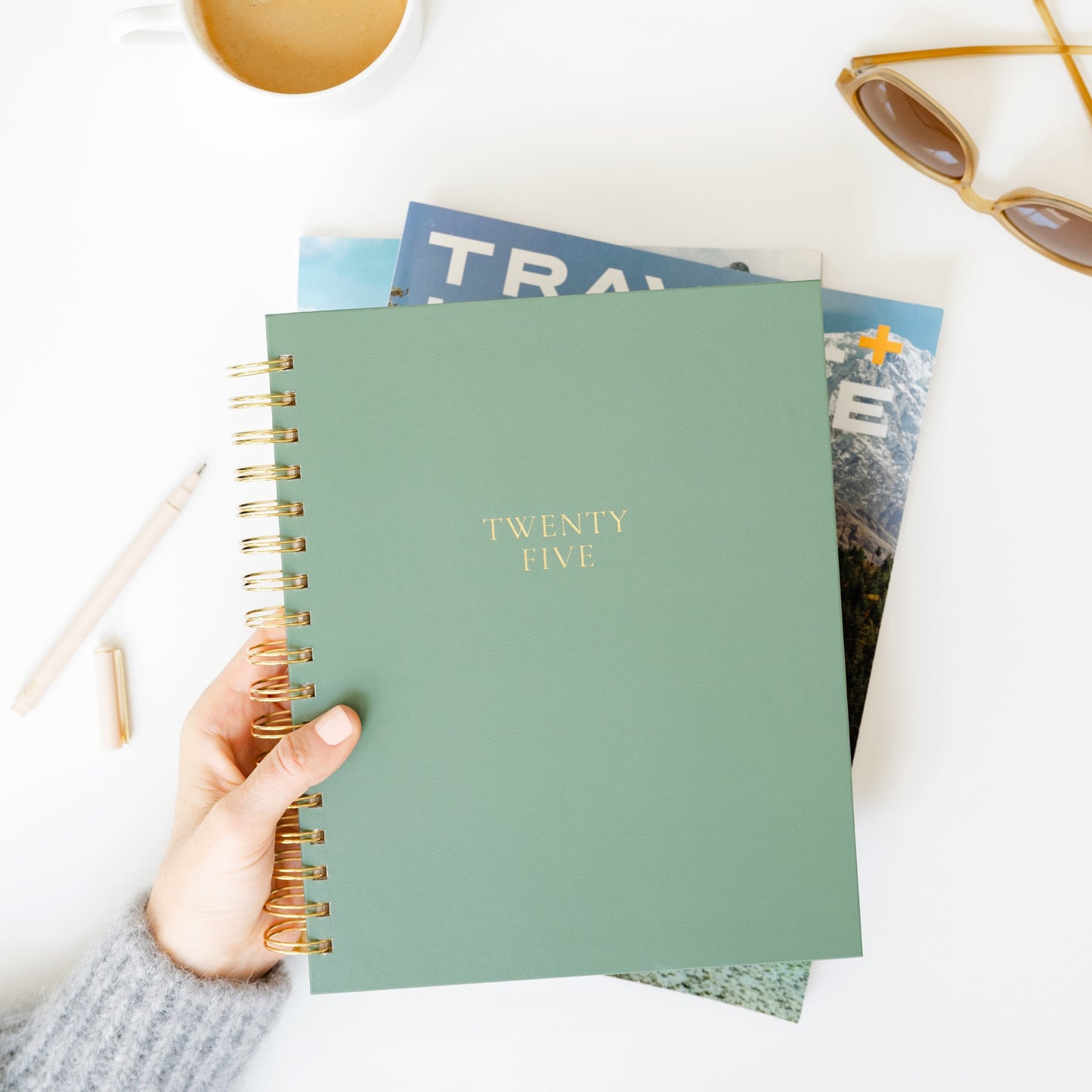 Sage green spiral planner on desk travel inspired