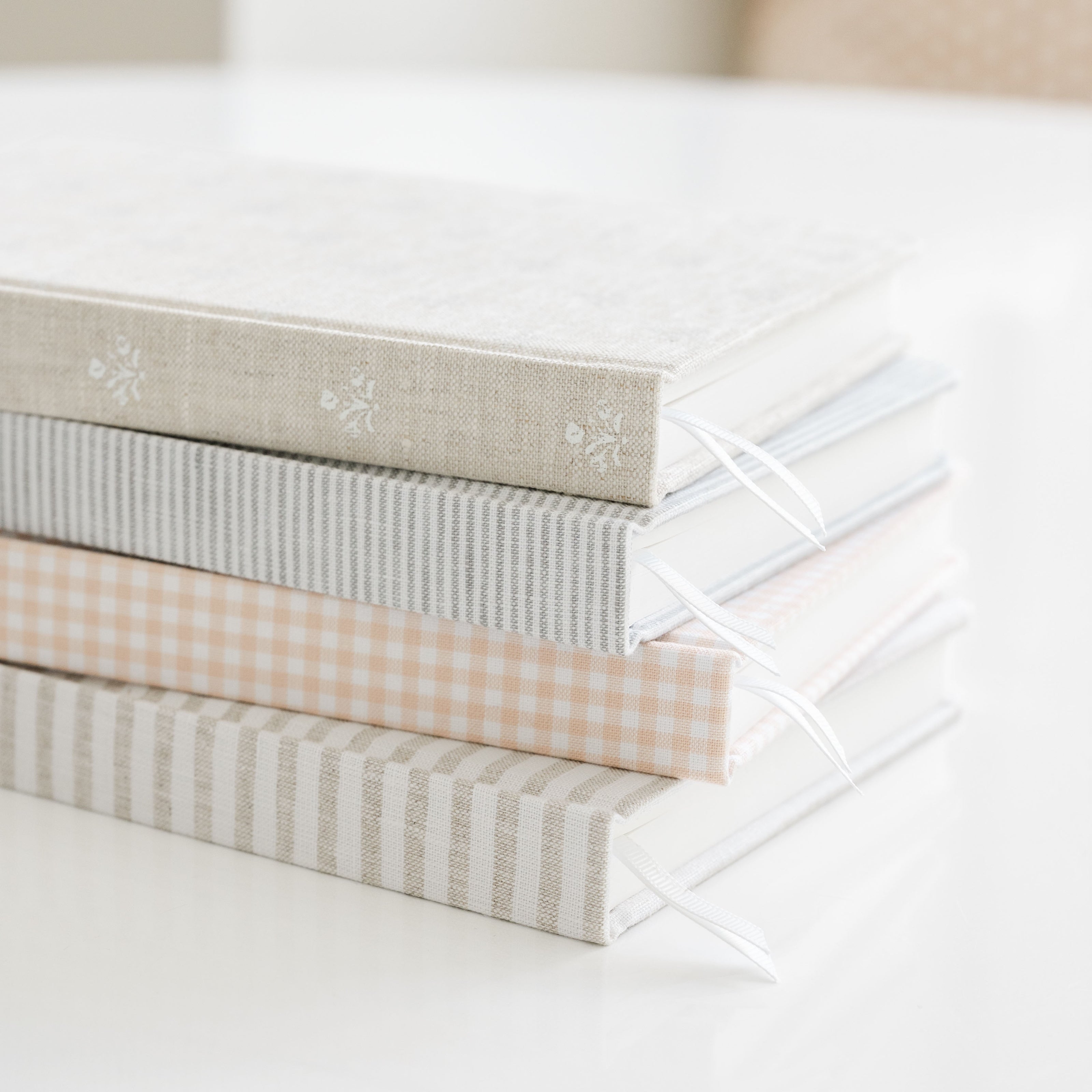Stack of fabric journals with different patterns on a white surfaces