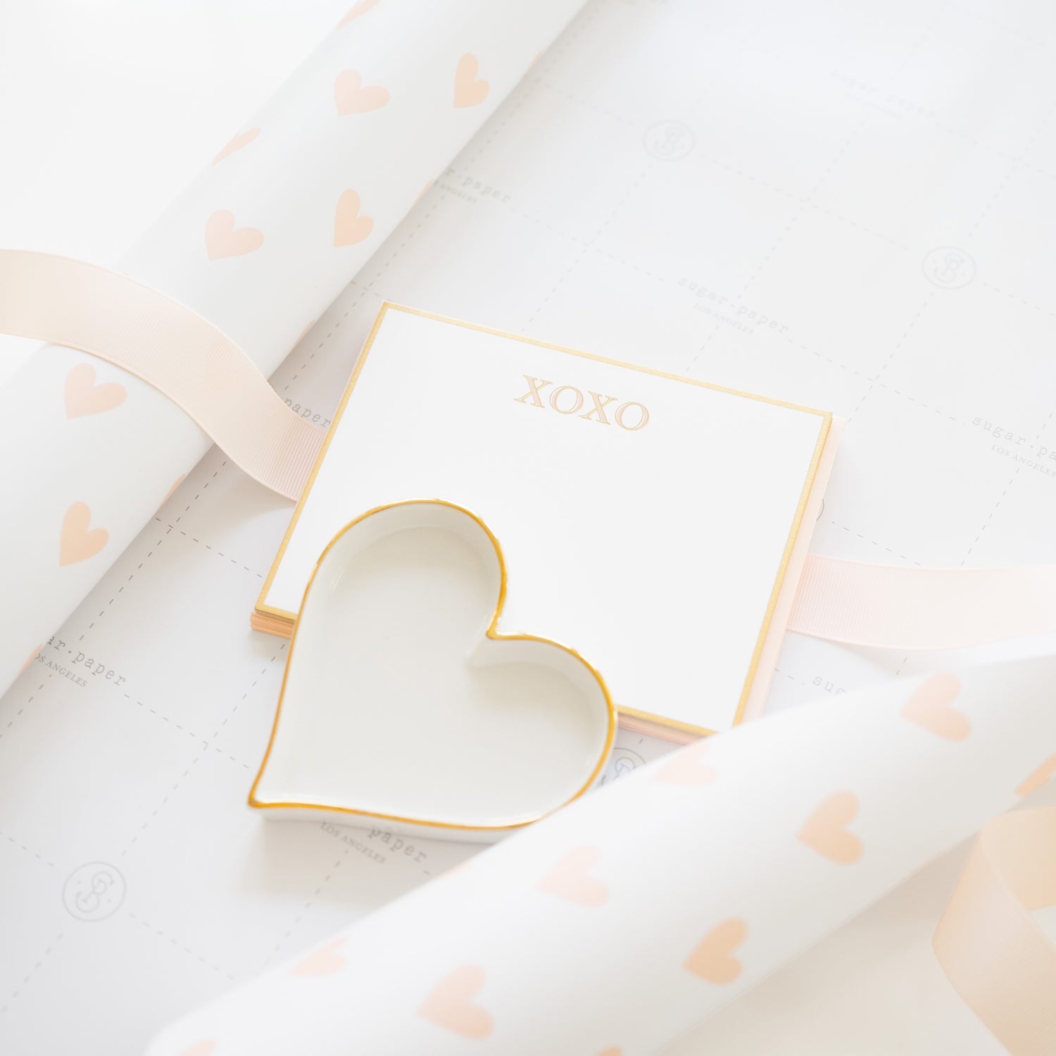 Heart gift wrap with xoxo gold note set and gold heart trinket tray being wrapped