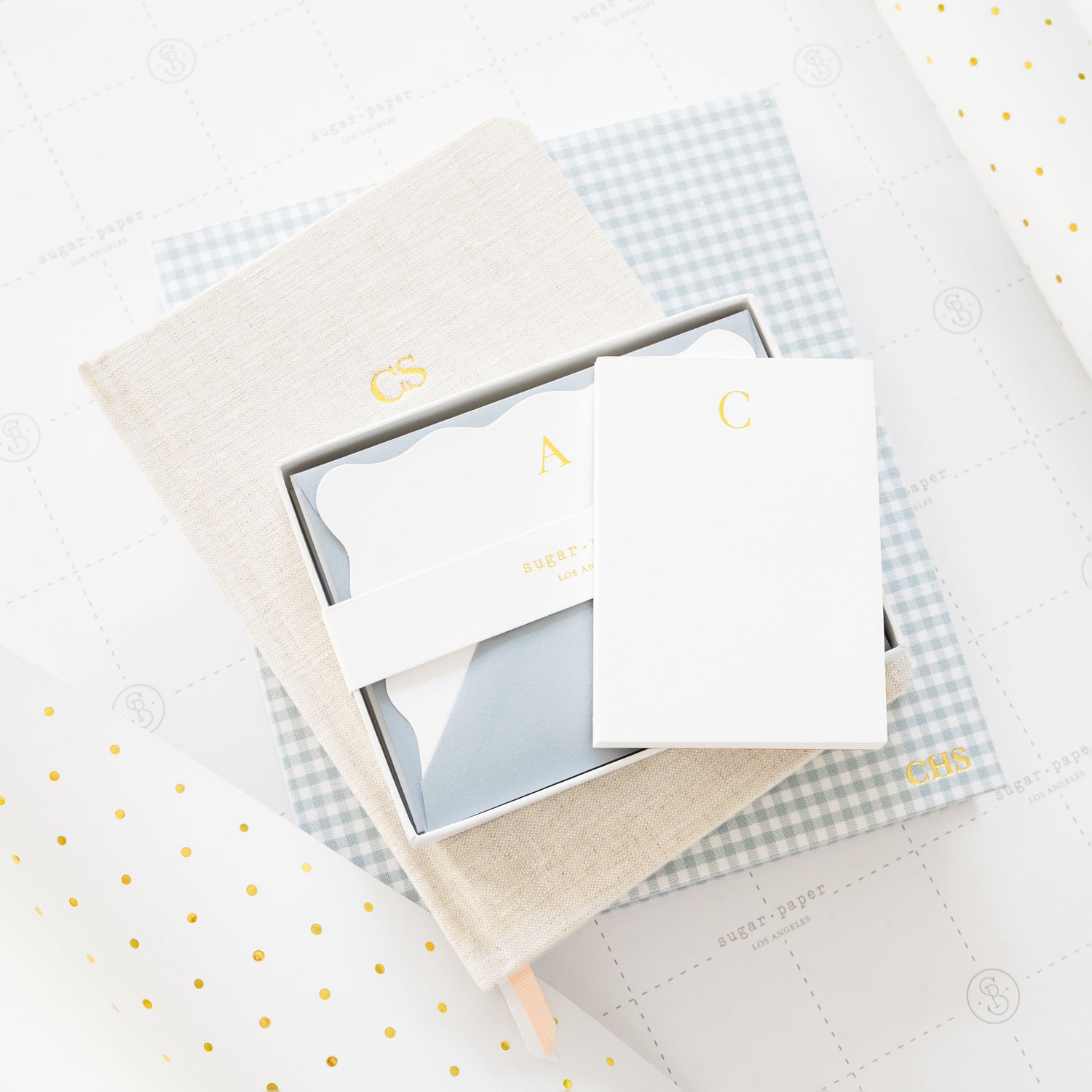 Set of stationery items including note cards and a pen on gift wrap with gold polka dots.
