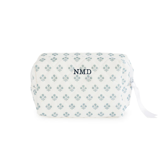 White pouch with blue floral pattern with a white ribbon zipper pull and white zipper embroidered with 'NMD' in blue thread