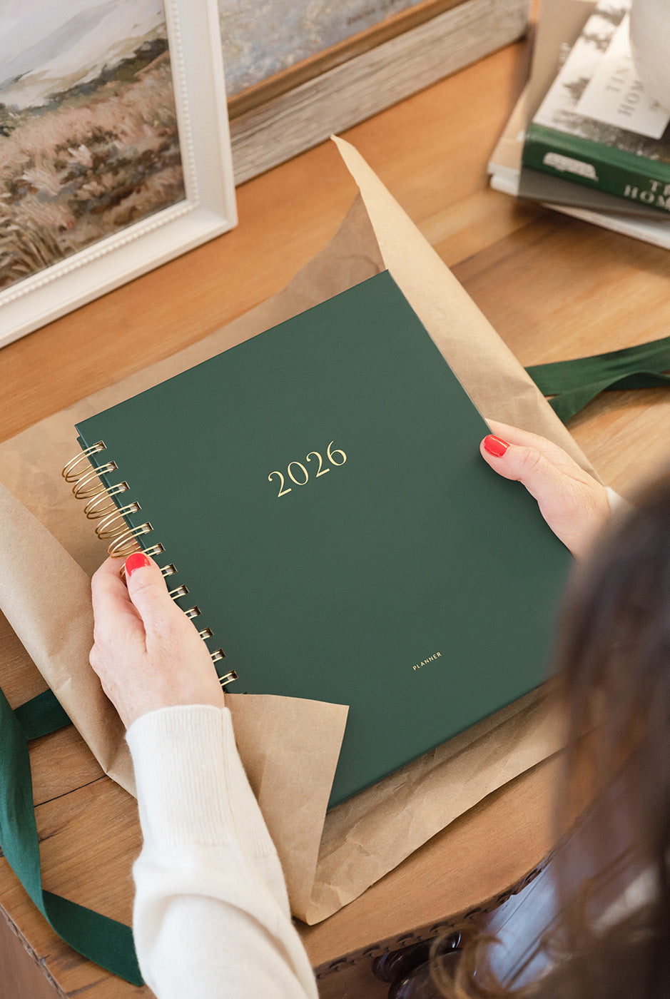 green planner with gold "2026" on the cover, being unwrapped