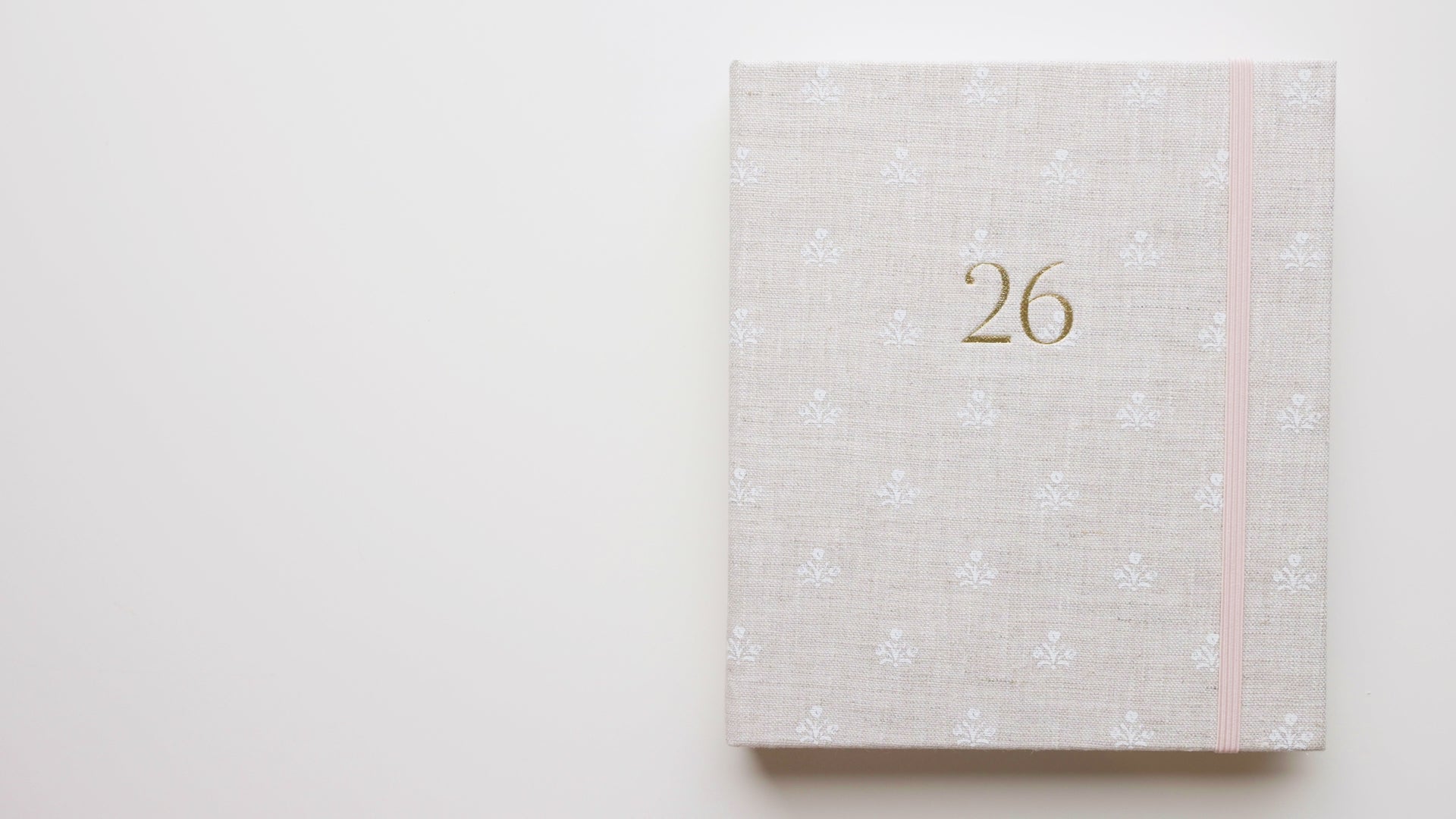 Load video: Interior of 2026 fabric bound concealed fabric planner in beige linen with white flower pattern and a pink elastic band