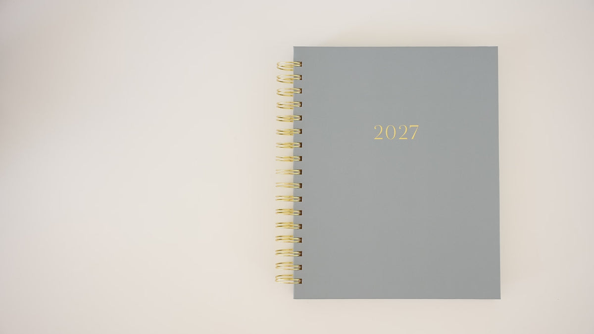 Load video: A person opening a 2027 blue signature spiral planner flipping through to show the interior page layouts