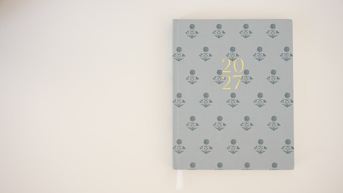 Load video: Someone opening a 2027 blue floral desk agenda flipping through to show the interior page layouts