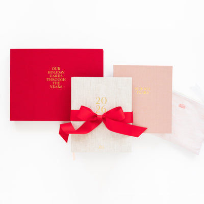 Red album, flax planner, pink keepsake book, and pink pouch on white background.