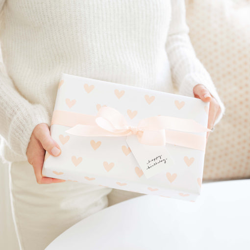 person holding a wrapped gift with a pink bow