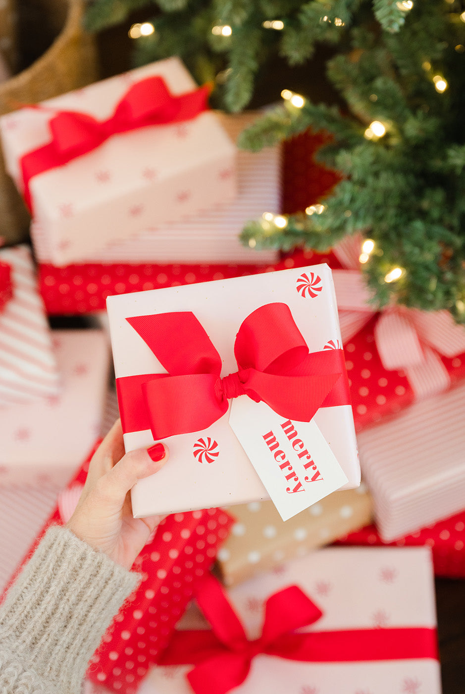 gifts wrapped in pink and white gift wrap under a Christmas tree
