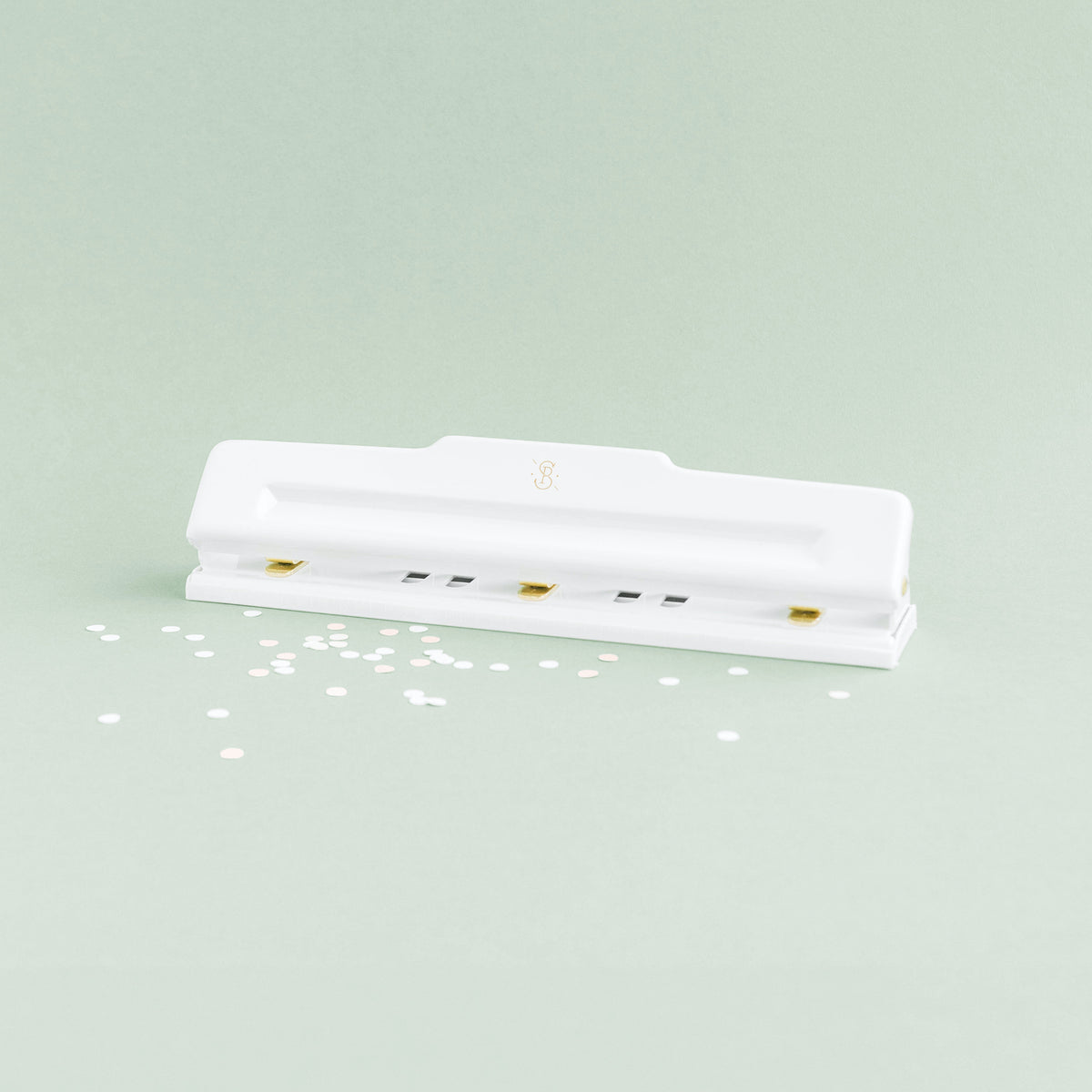white 3-hole-punch with scattered punched holes on green background