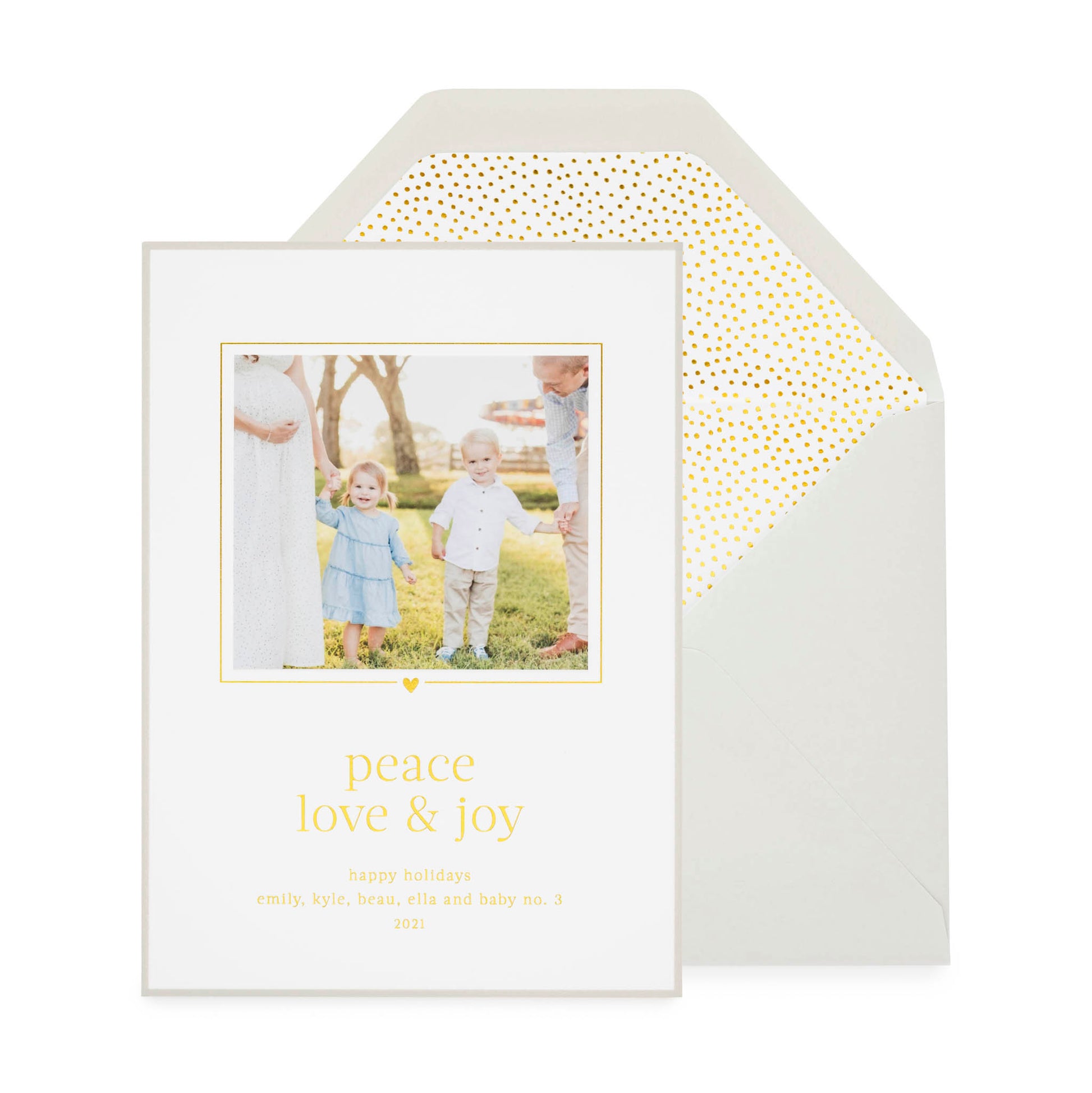 Custom holiday photo card printed with "peace love and joy" in gold foil with a photo of two kids and parents with a grey card border paired with a grey envelope open with a teensy dot gold foil envelope liner
