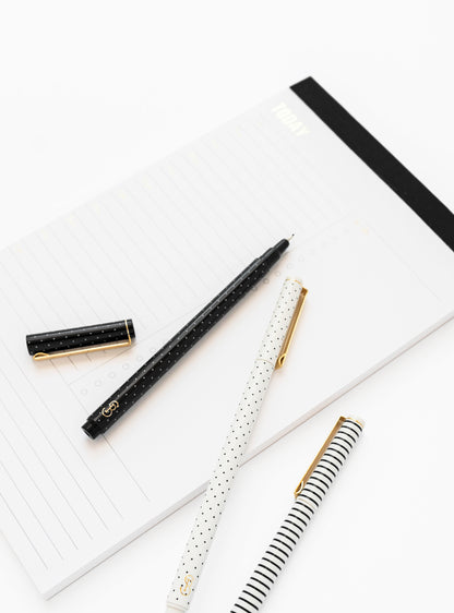 Black and white felt tip pens on black notepad