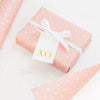 wrapped gift in rose dot wrapping paper with white and gold xo tag