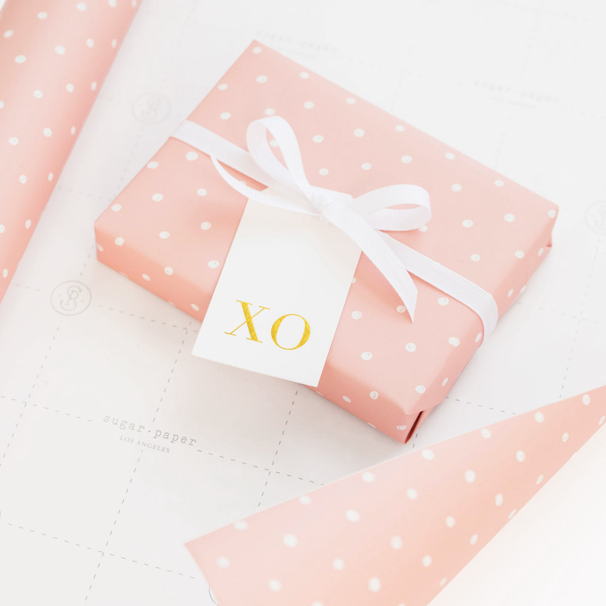 wrapped gift in rose dot wrapping paper with white and gold xo tag