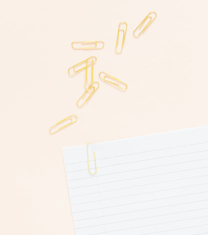 Gold paper clips on paper
