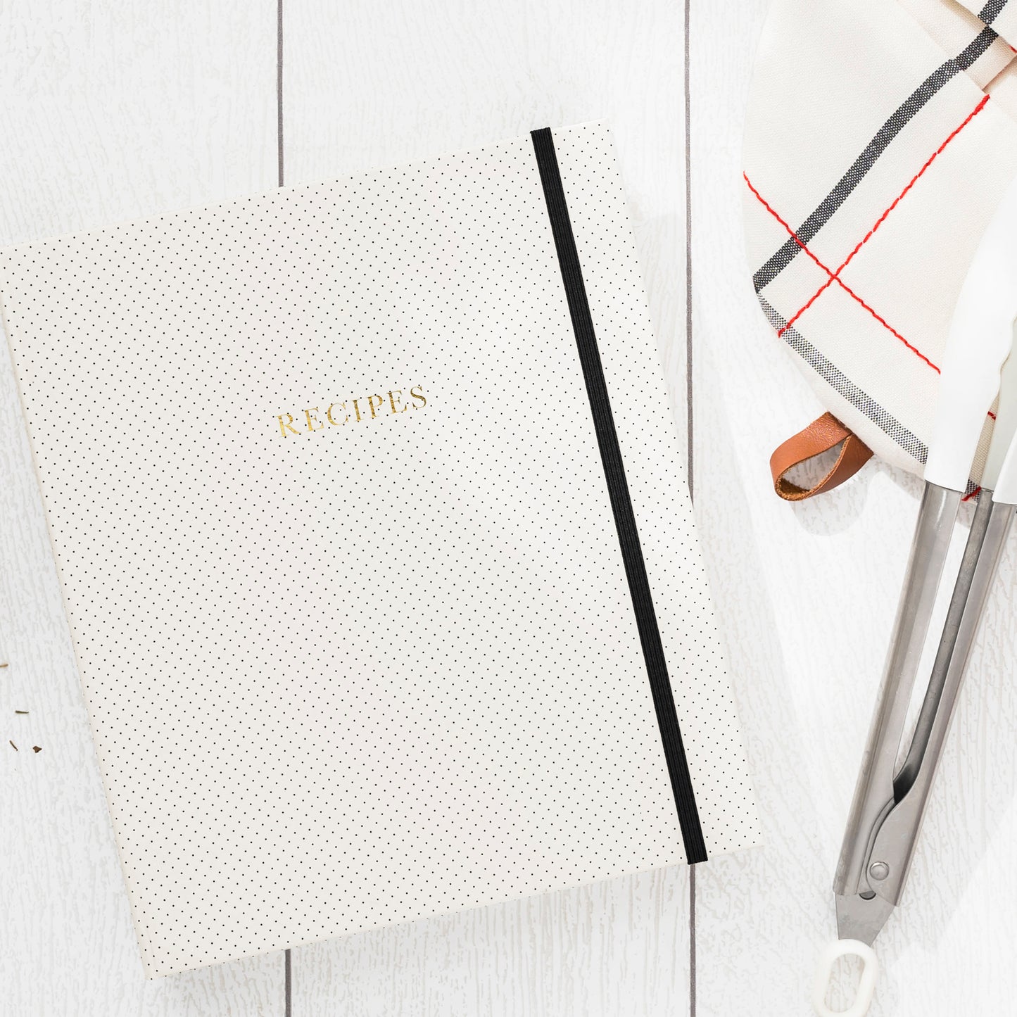 recipe book with tongs and linen towel