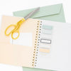 Gold scissors on notebook with page flags