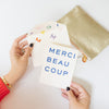 person holding merci beau coup card