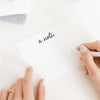 person writing on white note card