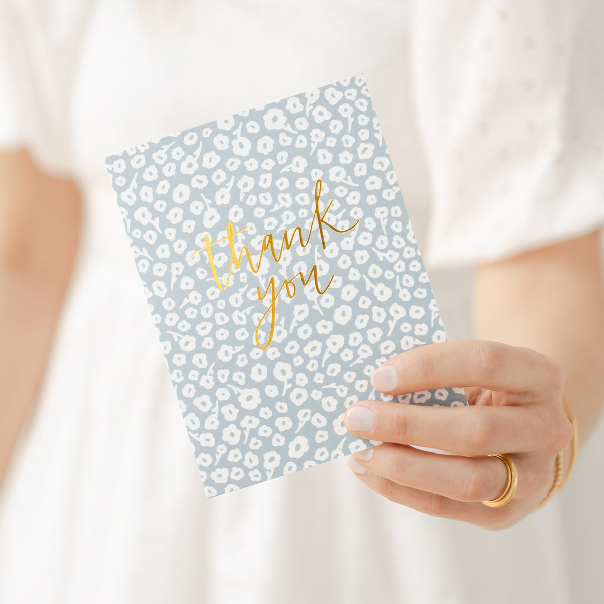 person holding blue floral thank you card
