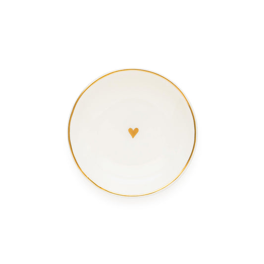 A white ceramic round trinket tray with gold details, including a gold heart in the center and a gold rim.